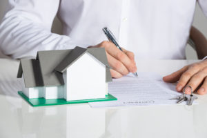 Midsection of businessman signing house contract at office desk